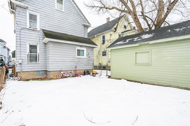 snow covered property featuring a shingled roof