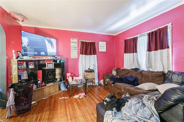 living area with a wood stove, crown molding, and hardwood / wood-style floors