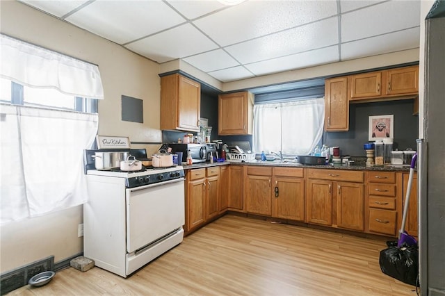 kitchen featuring white range with gas cooktop, brown cabinets, and a wealth of natural light