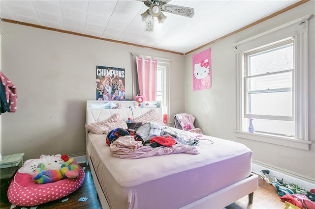 bedroom with crown molding, baseboards, and wood finished floors