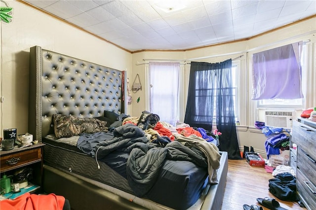 bedroom featuring cooling unit, wood finished floors, and crown molding