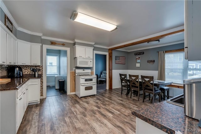 kitchen featuring dark wood-style flooring, crown molding, dark countertops, white cabinets, and white appliances