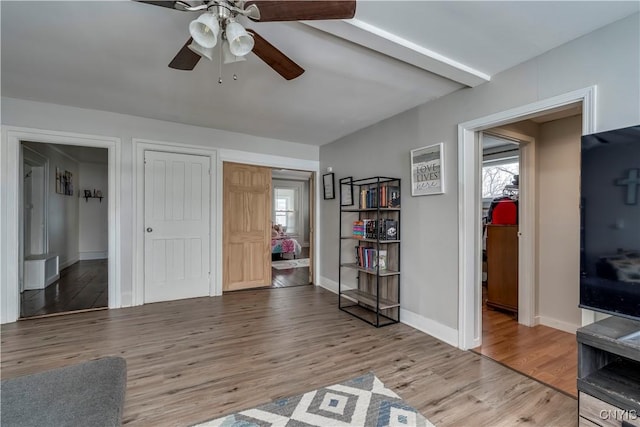 living area featuring a ceiling fan, baseboards, and wood finished floors