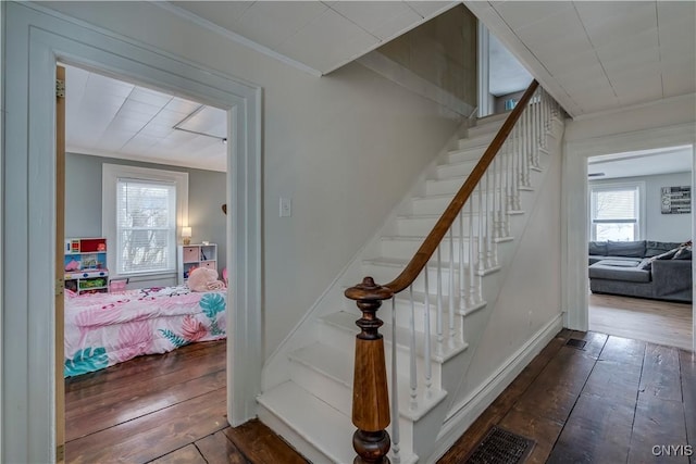 staircase with baseboards, crown molding, visible vents, and hardwood / wood-style floors