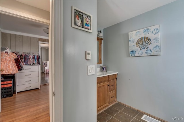 bathroom with wood walls, visible vents, wood finished floors, and vanity