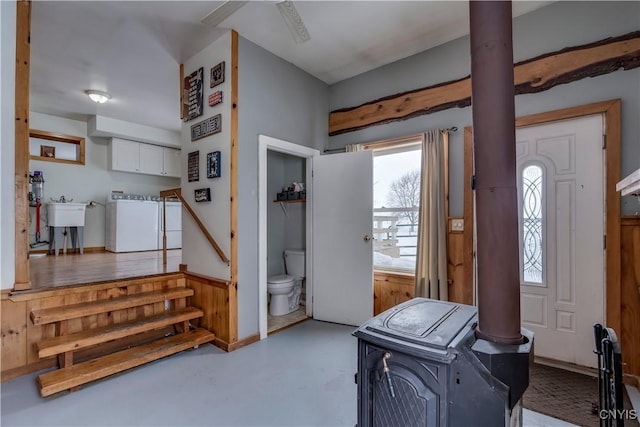 foyer entrance with a wood stove, concrete floors, and separate washer and dryer