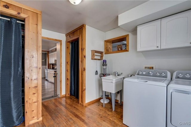 clothes washing area with cabinet space, wood-type flooring, baseboards, and washing machine and clothes dryer