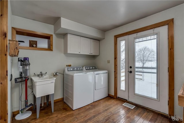 clothes washing area with cabinet space, baseboards, visible vents, hardwood / wood-style flooring, and independent washer and dryer