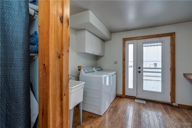 laundry room featuring cabinet space, baseboards, washer and clothes dryer, and light wood finished floors