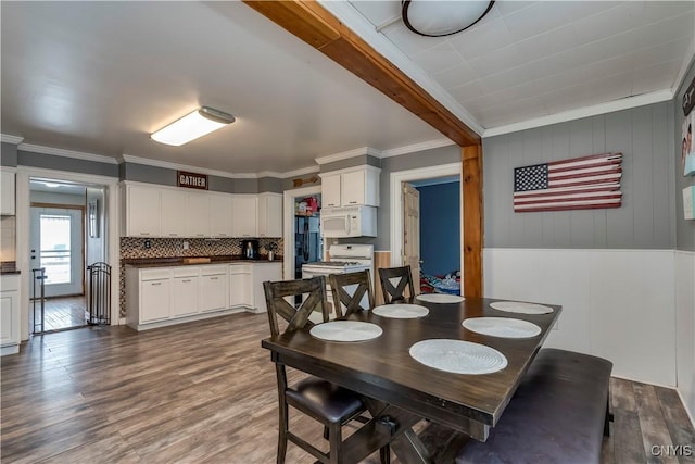 dining space featuring beam ceiling, ornamental molding, and wood finished floors