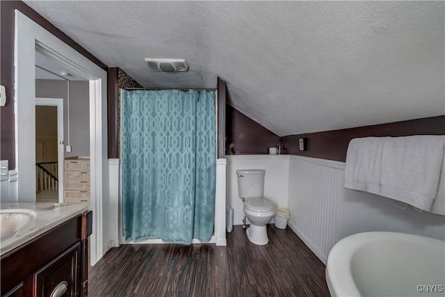 bathroom with visible vents, a wainscoted wall, wood finished floors, vaulted ceiling, and a textured ceiling