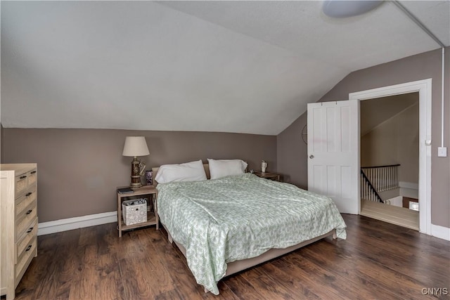 bedroom with lofted ceiling, dark wood-style floors, and baseboards