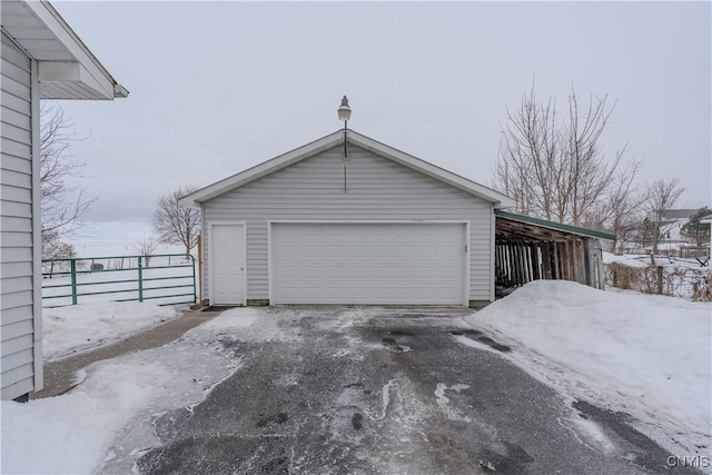 snow covered garage with a detached garage and fence