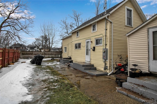 snow covered house featuring entry steps and fence