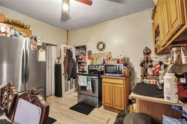 kitchen with light countertops, light wood-style flooring, appliances with stainless steel finishes, a ceiling fan, and a textured ceiling