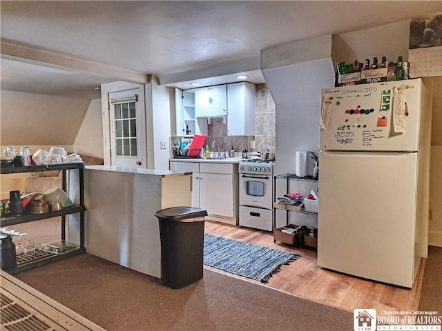 kitchen featuring tasteful backsplash, freestanding refrigerator, white cabinets, stainless steel gas range, and light wood-type flooring