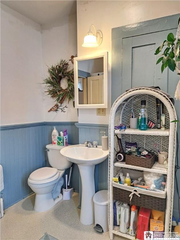 bathroom featuring a wainscoted wall and toilet