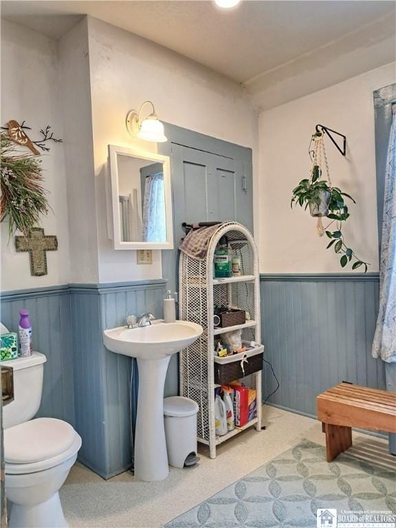 bathroom with a wainscoted wall and toilet