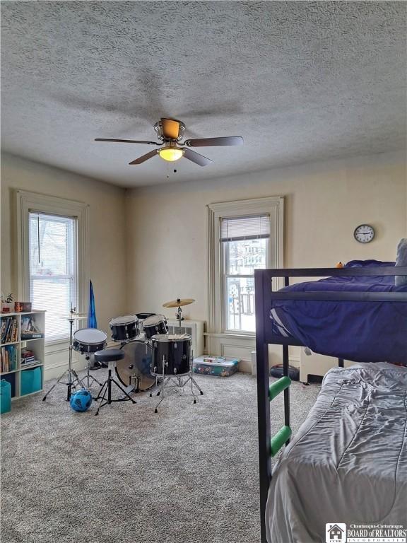 carpeted bedroom featuring ceiling fan and a textured ceiling