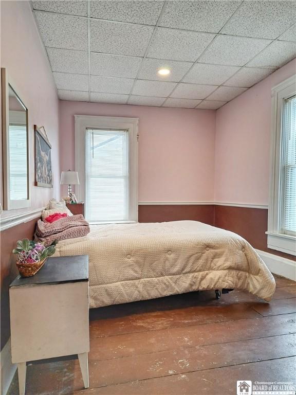 bedroom with a drop ceiling and hardwood / wood-style flooring