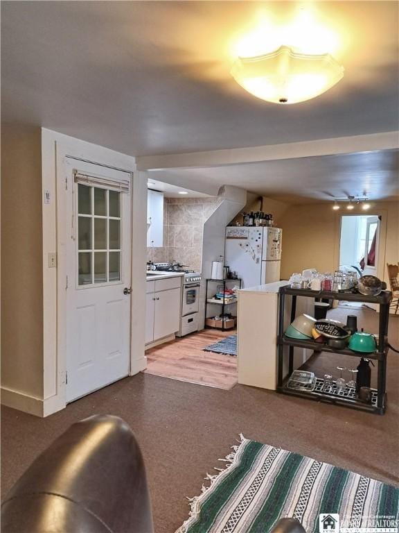 interior space with white cabinetry, baseboards, high end stainless steel range, freestanding refrigerator, and tasteful backsplash