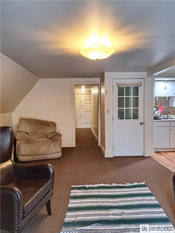 carpeted living area featuring lofted ceiling and baseboards