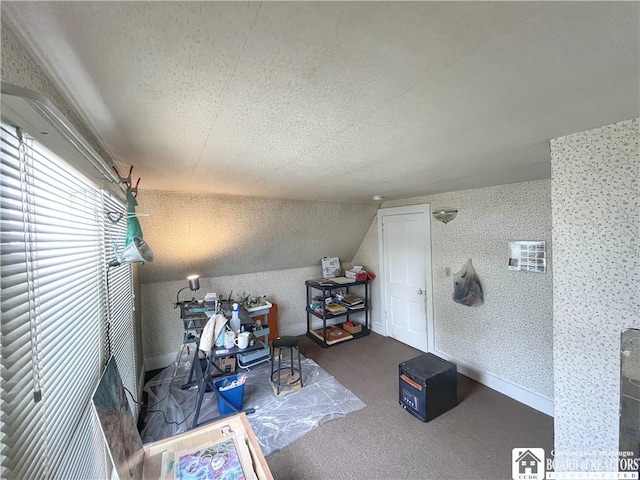 interior space with lofted ceiling, wallpapered walls, carpet floors, and a textured ceiling