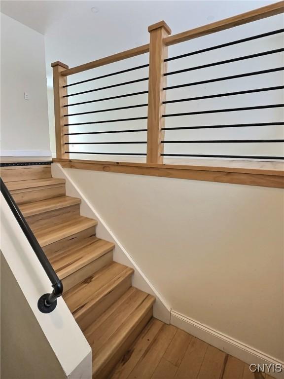 staircase featuring baseboards and wood finished floors