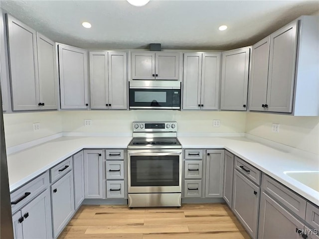 kitchen with light wood finished floors, gray cabinets, stainless steel appliances, and recessed lighting