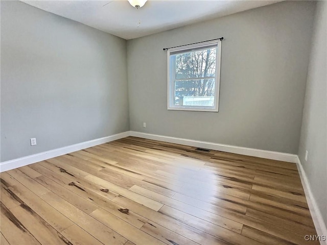 empty room with visible vents, baseboards, and wood finished floors