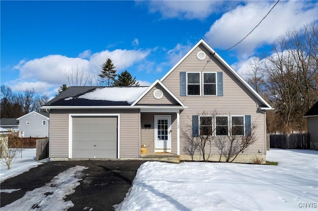 traditional home featuring a garage, fence, and aphalt driveway