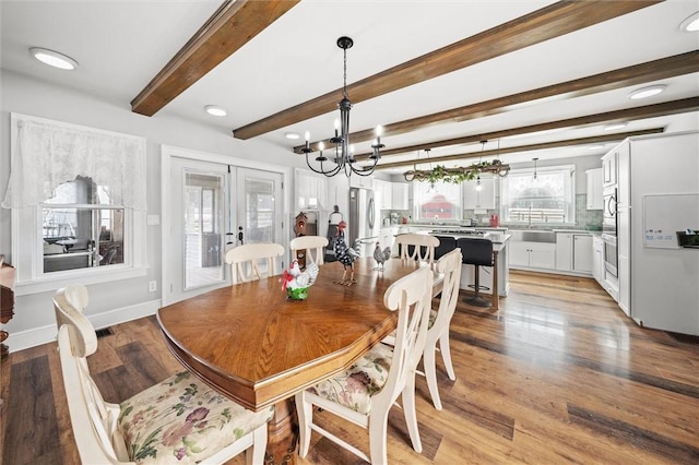 dining room featuring light wood-style flooring, a notable chandelier, baseboards, french doors, and beamed ceiling