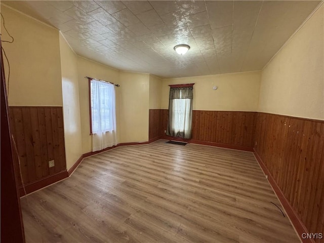 unfurnished room featuring wainscoting, wood finished floors, visible vents, and wooden walls