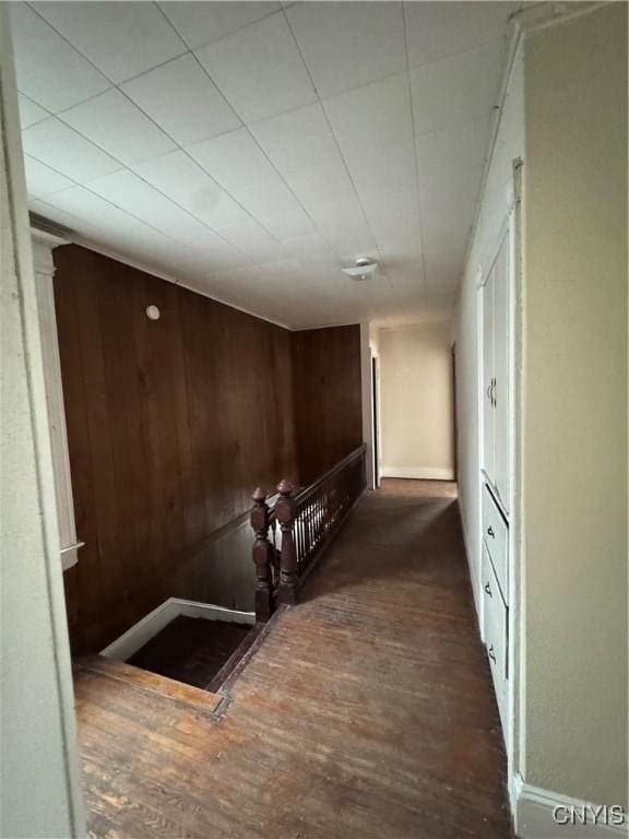 corridor with wooden walls, baseboards, and wood finished floors