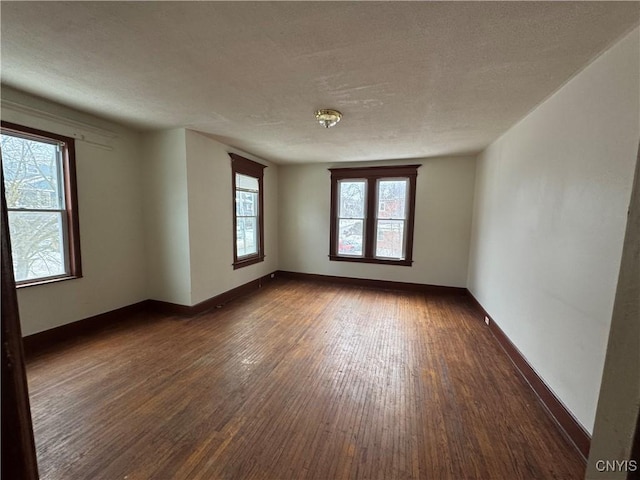 unfurnished room featuring a textured ceiling, baseboards, and dark wood-style flooring