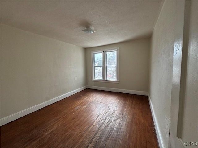 spare room featuring dark wood-style floors and baseboards