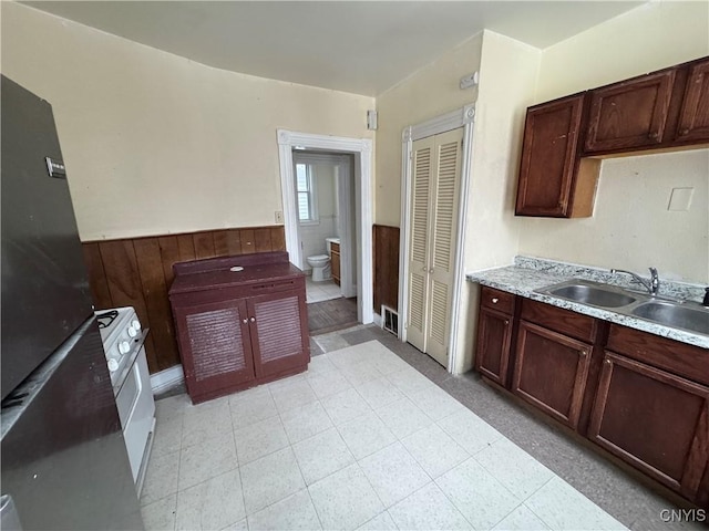 kitchen featuring light countertops, a wainscoted wall, a sink, and wooden walls