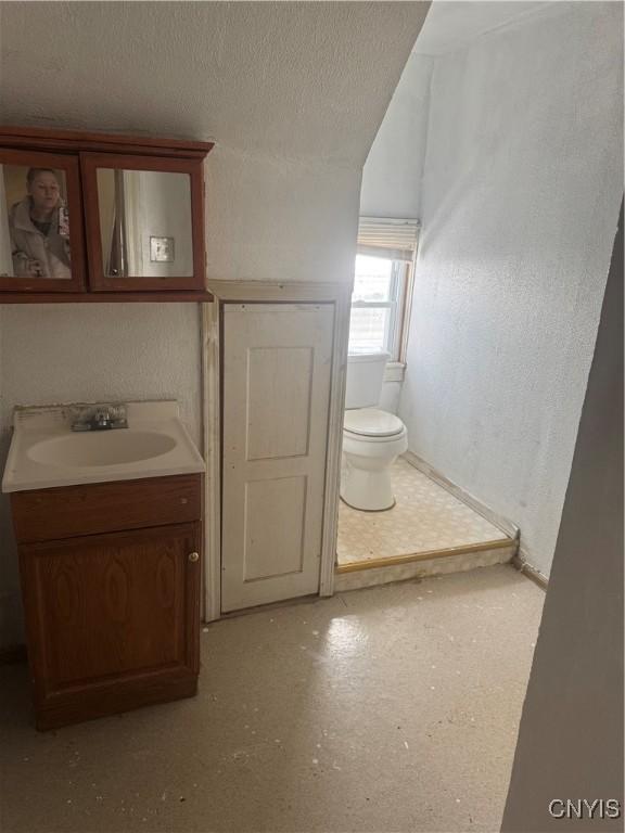 bathroom with a textured ceiling, vanity, and toilet