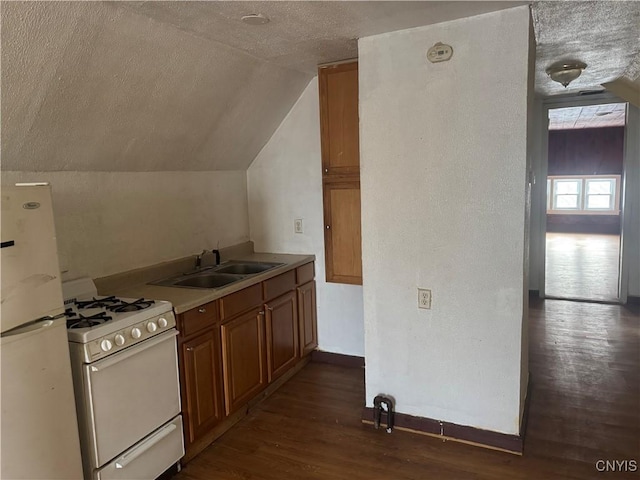 kitchen with white appliances, dark wood finished floors, brown cabinets, vaulted ceiling, and a sink