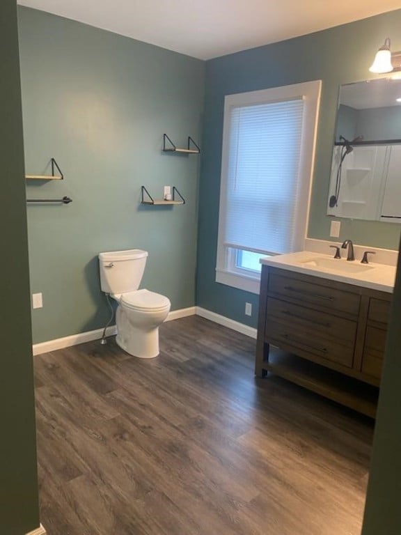 full bathroom with toilet, vanity, wood finished floors, baseboards, and walk in shower