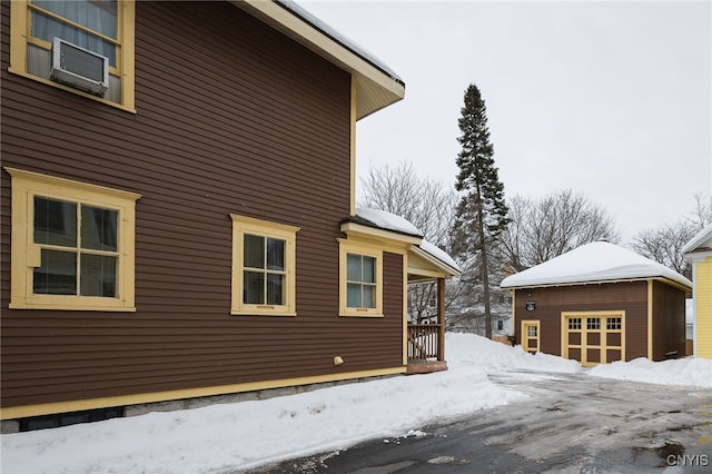 view of snowy exterior featuring cooling unit and an outdoor structure