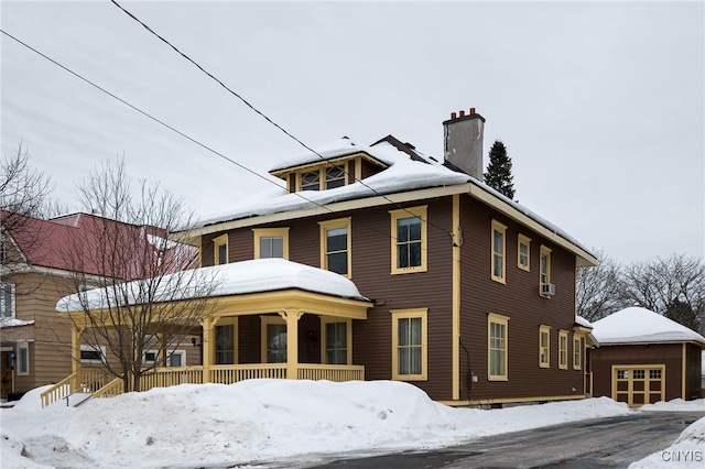 view of front of house featuring a porch, a chimney, and a garage