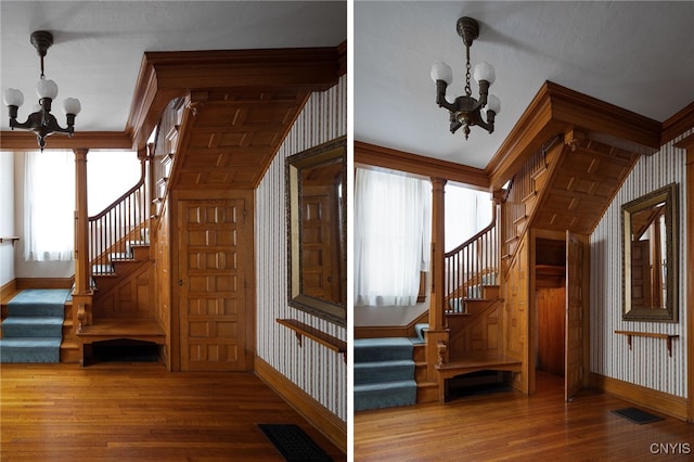 staircase with wallpapered walls, baseboards, a chandelier, and wood finished floors