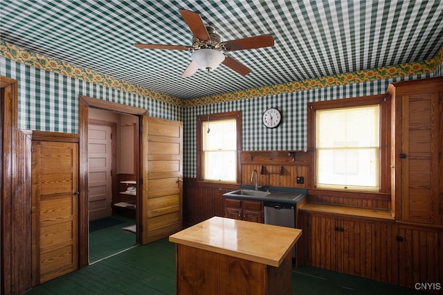 kitchen featuring wallpapered walls, dishwasher, a wainscoted wall, butcher block counters, and a sink