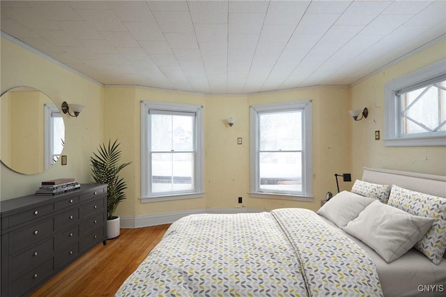 bedroom featuring ornamental molding, multiple windows, and wood finished floors