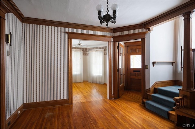 hallway featuring wallpapered walls, baseboards, hardwood / wood-style flooring, stairway, and an inviting chandelier