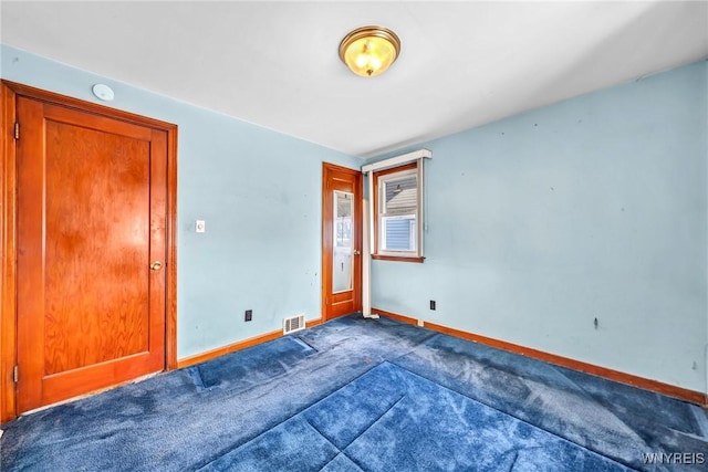 unfurnished room with visible vents, baseboards, and dark colored carpet