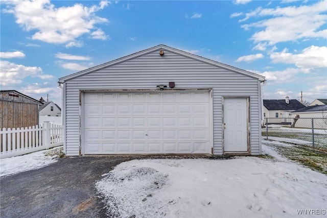 snow covered garage with a garage and fence