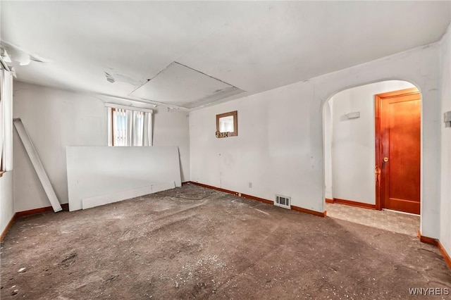 empty room with arched walkways, visible vents, and baseboards