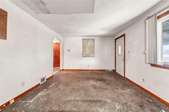 spare room featuring visible vents, arched walkways, and baseboards